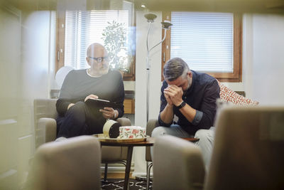 Therapist with depressed patient seen through glass