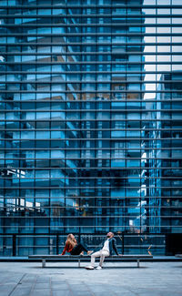 People sitting against modern building in city