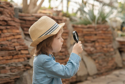 Preschooler boy inspecting desert cactus using magnifying glass. in the desert