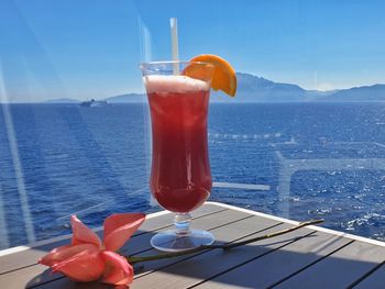 Drink on table by sea against sky