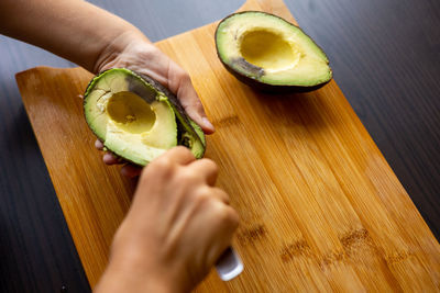 Cropped hands of woman holding watermelon on table