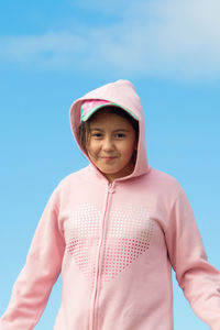 Portrait of a smiling girl standing against sky