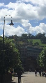 People on street amidst buildings in city against sky