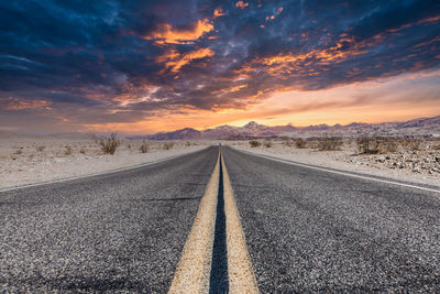 Surface level of road against sky during sunset