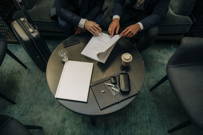 Midsection of businessmen discussing over contract at hotel lounge