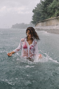 Full length of young woman splashing water