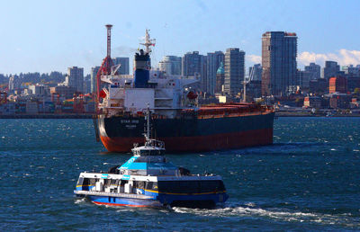 Boat sailing on sea by city against sky