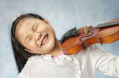 Close-up of cute smiling girl holding violin