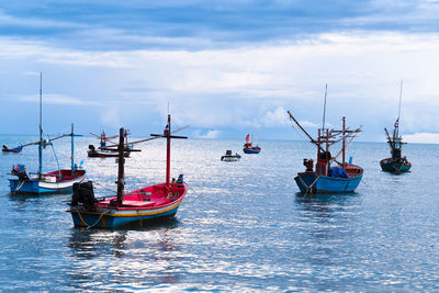 Sailboats moored in sea against sky