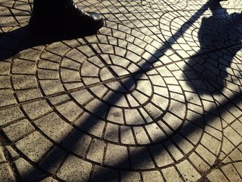 Low section of man shadow on tiled floor