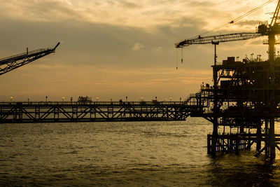 Cranes at harbor during sunset