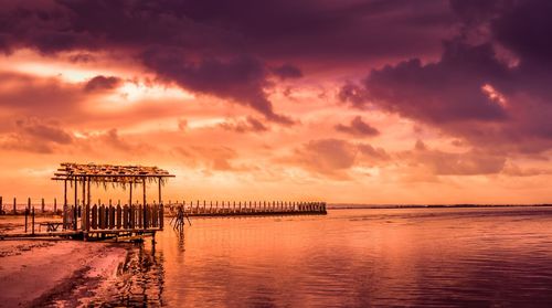 Pier over sea against sky during sunset