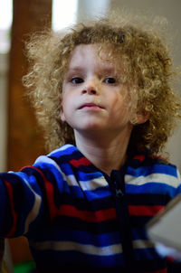 Portrait of cute boy with curly hair sitting at home