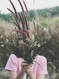 Woman holding flowers on field