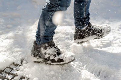 Photo of child's feet in winter boots walking in the snow.