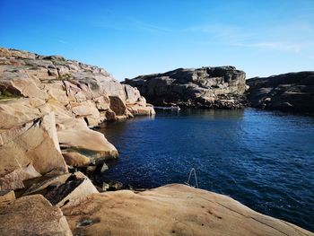 Scenic view of sea and rocks against blue sky