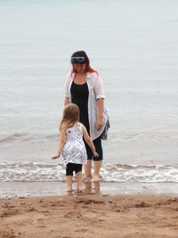 Mother and daughter standing at beach