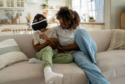 Young woman using mobile phone while sitting on sofa at home