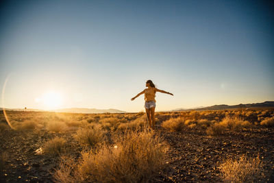 Woman standing on field at sunset