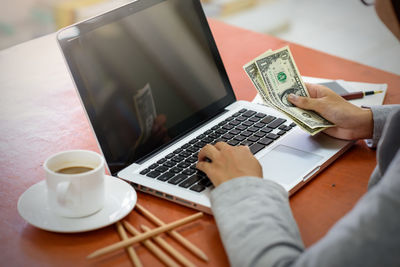 Midsection of man using laptop on table