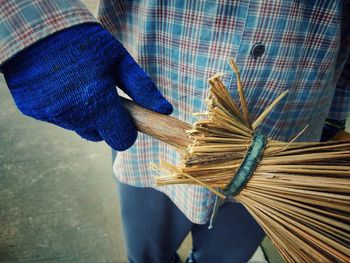 Midsection of man holding broom while standing outdoors