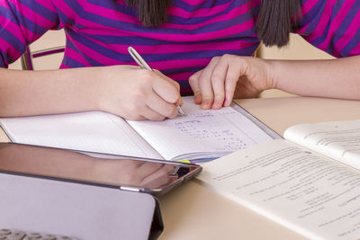 Midsection of woman reading book on table