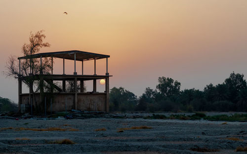 Abandoned house on field against sky during sunset