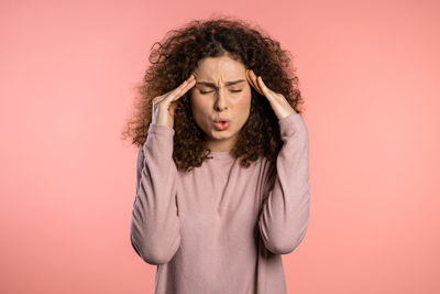 Portrait of young woman standing against red background