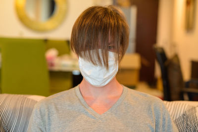 Man wearing mask sitting on sofa at home