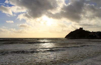 Scenic view of beach against cloudy sky