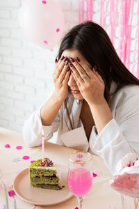  brunette woman in white party clothes preparing birthday table with cakes, cakepops, macarons 