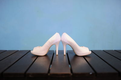 Close-up of high heels on wooden table against blue background