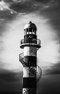 Low angle view of lighthouse by building against sky