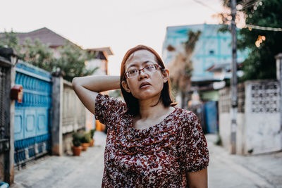 Portrait of young woman standing against building