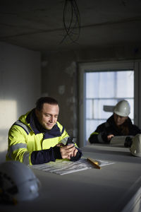 Male engineer at building site using cell phone