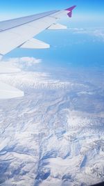 Aerial view of aircraft wing over landscape against sky