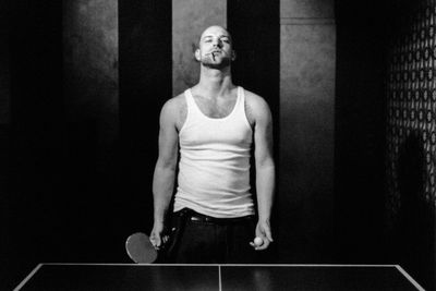 Portrait of man smoking cigarette while playing table tennis