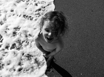 High angle view of shirtless girl standing on beach