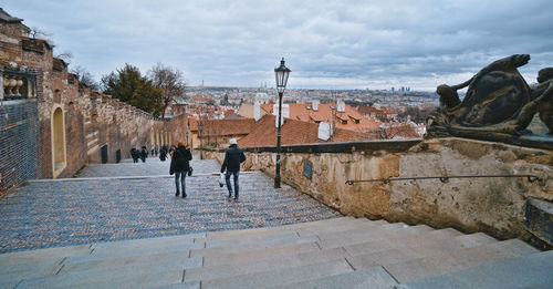 People walking on historical building in city against sky