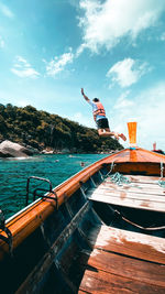 Man jumping on sea against sky