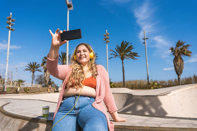 Young woman taking selfie through smart phone