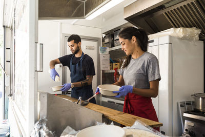 Young multi-ethnic male and female colleagues preparing food in food truck