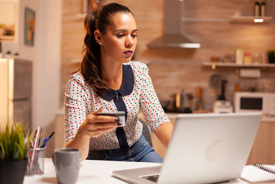 Young woman using laptop while standing in cafe