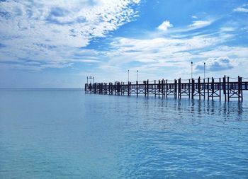 Pier on sea against cloudy sky