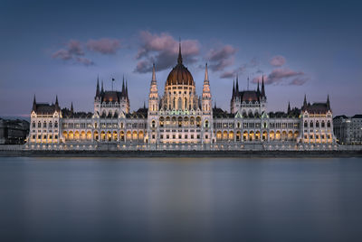 The hungarian parliament building from the opposite side of the danube river in the evening.