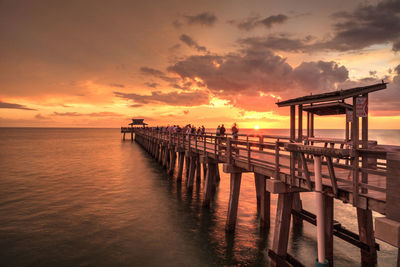 Pier over sea against sky during sunset