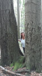 Woman leaning on tree trunk in forest