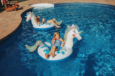 High angle view of girls sitting in inflatable rings on pool