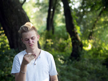 Young man looking at handkerchief in forest