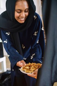 Muslim women wearing abayas gifting and sharing arabic sweets during ramadan